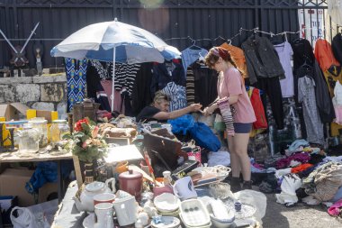 Hayfa, İsrail, 28 Mart 2025, kestane rengi saçlı ve başörtüsü takan bir kadın ayakta durup bir şeyi incelerken, siyah saçlı diğer kadın oturuyor ve ona yardım ediyor gibi görünüyor..