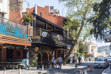İstanbul, Türkiye, 2 Mayıs 2024, Arnavut bölgesi sokak manzaralı renkli ve turuncu binalar, kafe Angelo, dükkanlar ve buradan geçen insanlar.