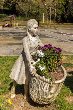 İstanbul Emirgan Parkı 'nda elinde çiçek sepeti tutan bir kızın taş heykeli. Peyzaj tasarımı