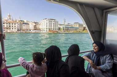 İstanbul, Türkiye, 2 Mayıs 2024, İstanbul 'dan feribotla geçen turistler, Galata Kulesi ve şehir silueti manzaralı.