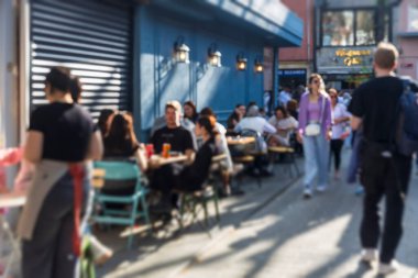Tanımlanamayan insanlarla dolu bulanık bir fotoğraf. İstanbul 'un Uskudar kentindeki bir kafede arka planda büyük bir ağaç bulunan açık hava masalarında dinlenen insanlar.