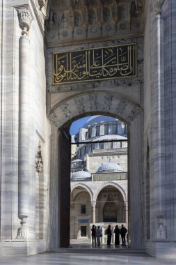 İstanbul, Türkiye, 2 Mayıs 2024, Süleyman Camii 'nin kubbeleri ve iç avlusunun çerçeve manzarası İslami yazıyla süslenmiş taş bir geçitten görülüyor .