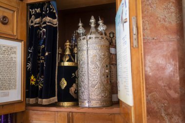 Hayfa, İsrail, 5 Nisan 2025, Aram Tzova Sinagogu 'nun iç görünümü. Ahşap bir dolabın içinde çok sayıda gümüş süslemeli Sefer Torah tomarları ve koyu mavi işlemeli Parochet (Tevrat kemer perdesi) sergiliyor..
