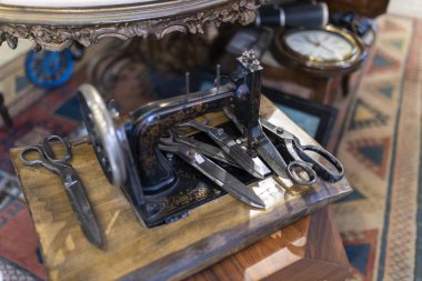 İstanbul, Türkiye, 2 Mayıs 2024, Vintage Singer 221 Tüy sıklet dikiş makinesi, çeşitli makas ve antika eşyalar ile çevrelenmiş, muhtemelen bit pazarındaki bir dükkan veya antikacıda sergilenmektedir.