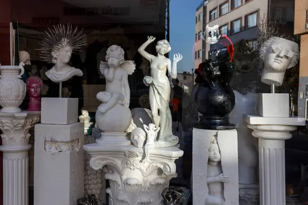 İstanbul, Türkiye, 2 Mayıs 2024, mağaza vitrininde klasik figürler, melekler ve dekoratif unsurlar da dahil olmak üzere çeşitli alçı heykeller ve büstler sergileniyor.