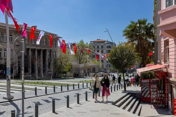 İstanbul, Türkiye, 2 Mayıs 2024, Beyolu ilçesindeki sokak sahnesinde, sokakta çeşitli bina ve ağaçlarla süslenmiş Türk bayrakları ve afişleriyle süslenmiş yayalar üzerinde yürüyen insanlar görülüyor.