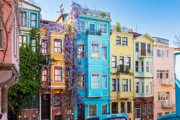 İstanbul, Türkiye, 2 Mayıs 2024, Balat ilçesindeki meşhur renkli evler, canlı cepheler ve çiçek açan mor salkımlarla kaplı.