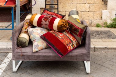 Tel Aviv-Jaffa, İsrail. 9 Nisan 2025, Tel Aviv 'in eski Jaffa bölgesinde bir dükkanın önünde satılık renkli dekoratif yastıklarla dolu gri bir döşeme..