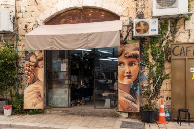 Tel Aviv-Jaffa, İsrail. 9 Nisan 2025, Tel Aviv 'in eski Jaffa bölgesindeki girişin her iki tarafında da sanatsal tablolar olan bir dükkan..
