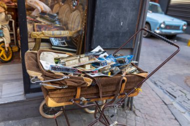 İstanbul, Türkiye, 5 Nisan 2024, İstanbul, Türkiye 'deki bir antikacının önünde içi oyuncak dolu bebek arabası. Caddeye park edilmiş mavi araba..