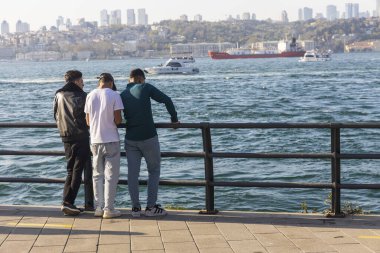 İstanbul, Türkiye, 5 Nisan 2024, İstanbul, Türkiye 'de İstanbul, Türkiye' de İstanbul 'a bakan korkulukların yanında duran üç genç adam, kentin ufuk çizgisi uzaktayken