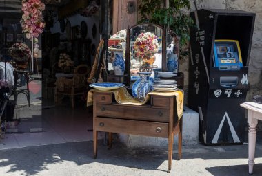 Hayfa, İsrail, 16 Nisan 2025, ayna ve çeşitli seramik eşyalar sergilenen Vintage şifonyer Hayfa, İsrail 'de bir mağazanın önünde. Sağ tarafta bir ATM var.