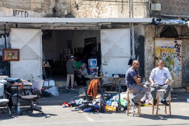 Hayfa, İsrail, 16 Nisan 2025, Orta Doğulu gibi görünen iki adam, İsrail 'in Hayfa kentindeki dağınık bir dükkan veya market tezgahının önünde oturuyorlar..