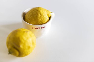 İki parlak sarı limon temiz beyaz bir yüzeye yerleştiriliyor. Bir tanesi el yazısıyla 