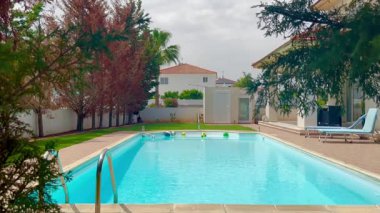 Larnaca, Kıbrıs, 8 Mayıs 2025, Kıbrıs Rum Kesimi 'nin Meneou kentindeki bir villada parçalı bulutlu bir gökyüzünün altında ferahlatıcı bir yüzme havuzu bulunuyor.