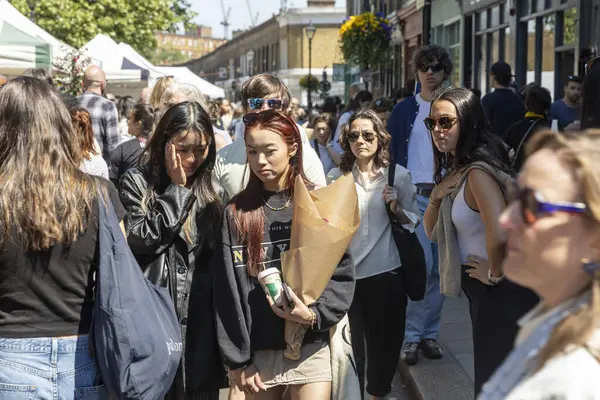 Londra, İngiltere, 10 Mayıs 2025, Londra 'da güneşli bir günde kalabalık bir açık hava pazarında çeşitli insanlar geziniyor..