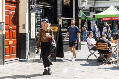 Londra, İngiltere, 10 Mayıs 2025, Covent Garden yakınlarındaki bir sokak gezginler ve açık hava kafelerle dolu..