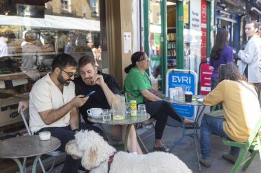 Londra, İngiltere, 15 Mayıs 2025, İnsanlar Londra 'da bir dükkanın önündeki açık masalarda kahve ve sohbetten hoşlanırlar..