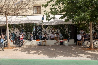 Tel Aviv, İsrail, 22 Mayıs 2025, Florentin Mahallesi 'nde bir kafenin önünde grafiti sanatıyla sosyalleşen insanlar..