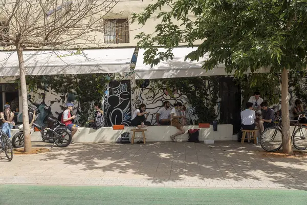 Tel Aviv, İsrail, 22 Mayıs 2025, Florentin Mahallesi 'nde bir kafenin önünde grafiti sanatıyla sosyalleşen insanlar..