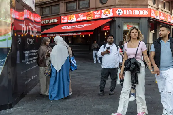 Londra, İngiltere, 5 Mayıs 2025, Şehir Caddesindeki Fast Food Restoranı. Türbanlı Müslüman kadınlar ayakta duruyor