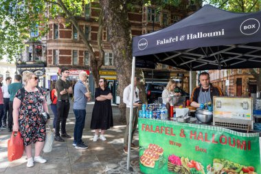 Londra, İngiltere, 5 Mayıs 2025, Falafel ve Halloumi satan bir adam açık hava pazarında.
