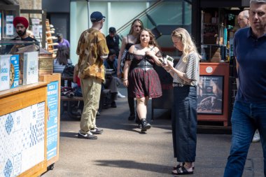 Londra, İngiltere, 5 Mayıs 2025, Bir grup insan kalabalık bir açık hava pazarında yürüyor ve ayakta duruyor. Spitalfields pazarı. 