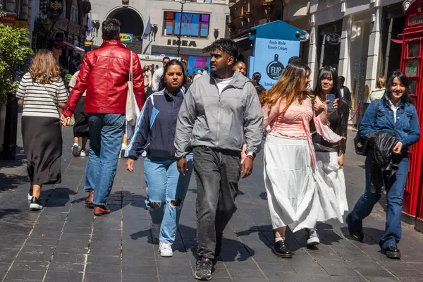 Londra, İngiltere, 5 Mayıs 2025, Oxford caddesinde IKEA 'nın yanındaki kalabalık caddede yürüyen bir grup insan.