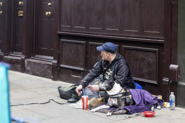 Londra, İngiltere, 7 Mayıs 2025 dilenci bir adam ve boğa teriyeri yolda oturup yalvarıyor..
