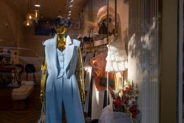 Bir Giysi Mağazası Vitrininde Manken Gösterimi. Altın rengi bir manken üzerinde yelek olan üç parçalı mavi takım elbise.