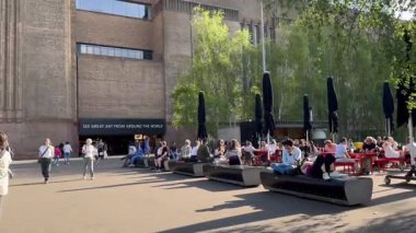 Londra, İngiltere, 5 Mayıs 2025, Tate Modern 'in cephesi. İnsanlar banklarda oturup konuşuyorlar..
