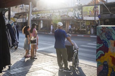 Petah Tikva, İsrail, 12 Haziran 2025, Bir grup yetişkin ve bir çocuk caddenin yanındaki kaldırımda duruyor..