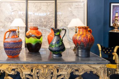 London, UK, 15 May 2025,  A display of vibrant mid-century modern Fat Lava pottery vases on an ornate table.