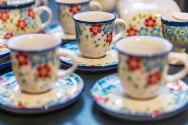 Renkli çiçek desenli çömlek fincanları, geniş bir pazarda sergileniyor.