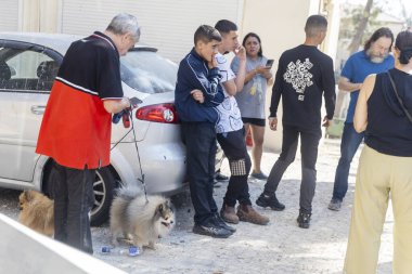 Hayfa, İsrail, 22 Haziran 2025 İnsanlar ve köpekler sokakta bir arabanın etrafında toplanıyor. Bir İran füzesi Adar bölgesindeki bir fıskiyeyi ve binayı vurdu. İsrail-İran Savaşı..
