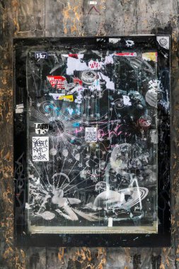 Londra, İngiltere, 12 Mayıs 2025, göksel ve soyut tasarımlı çıkartma kaplı bir bilgi panosu dokulu bir duvara yapıştırılmıştır..