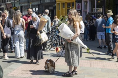 Londra, İngiltere, 12 Mayıs 2025, Londra 'da alışveriş merkezleri ve bisikletleri olan kalabalık bir caddede insanlar ve köpekler