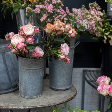 Metal kovalarda çeşitli pembe çiçekler metal bir masada sergilenir..