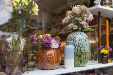 Çeşitli Vazolarda Renkli Çiçekler Bir Dükkan Penceresinde Gösteriliyor.