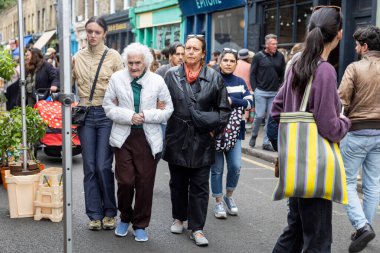 Londra, İngiltere, 9 Mayıs 2025, Kalabalık Bir Sokakta Yürüyen Çeşitli İnsanlar Grubu. Kızı ve torunuyla yaşlı bir kadın.