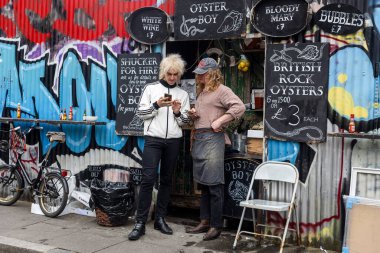 Londra, İngiltere, 9 Mayıs 2025, İki Adam Graffiti Sanatıyla Bir İstiridye Bar Dükkanında Bekliyor.