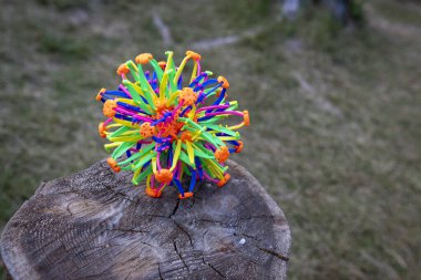 Canlı, genişletilebilir bir oyuncak top, Hoberman küresi olarak adlandırılır, açık havada bir ağaç kütüğünün üzerinde dinleniyor..