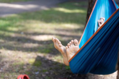 Çam ormanında mavi bir hamakta sallanan bir topuk..