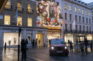 Londra, İngiltere, 20 Aralık 2024, Dior ve Chanel 'in zarif vitrinleriyle çelişen deniz atı temalı bir Noel' in ya da şenlikli bir dekorasyonun canlı gösterisi bir binayı süslüyor..