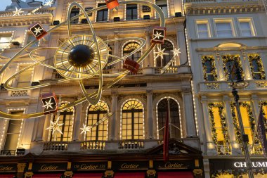 Londra, İngiltere, 2 Aralık 2024 altın yıldız ve hediye sergisi ile aydınlatılmış Cartier mağazası çevredeki binalar üzerine şenlikli süslemeler