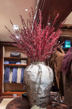 Londra, İngiltere, 23 Kasım 2025, Ralph Lauren 'ın şık iç mimarisi büyük gri kışlık böğürtlen vazosu, zarif çiçek aranjmanı, lüks giysi sergisi ve sıcak lüks atmosfer.