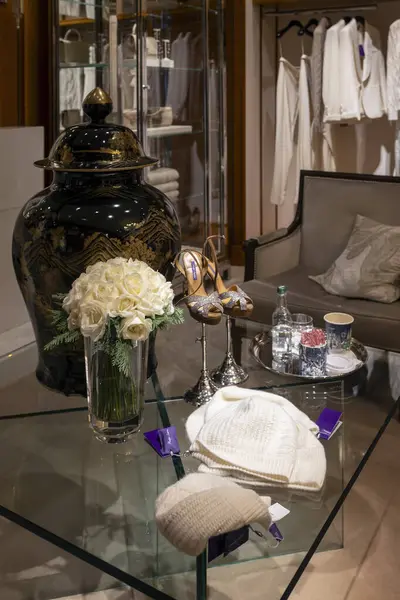Londra, İngiltere, 24 Kasım 2024. Bir Ralph Lauren mağazasının içinde cam sehpanın sergilendiği siyah ve altın seramik bir vazo ve beyaz güllerden oluşan açık bir vazo.