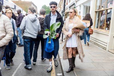 Londra, İngiltere, 5 Mayıs 2025, kalabalık bir açık hava pazarında çiçek ve bitkilerle yürüyen genç çift.