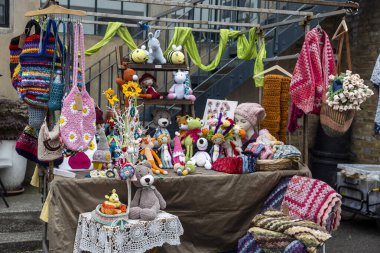 Londra, İngiltere, 14 Mayıs 2025, Bir açık pazar tezgahı birçok el yapımı örgü, çanta, battaniye, şapka, doldurulmuş hayvanlar ve dekoratif parçalar gösteriyor, 