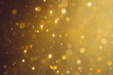Siyah arkaplanda koyu soyut altın bokeh parıltısı